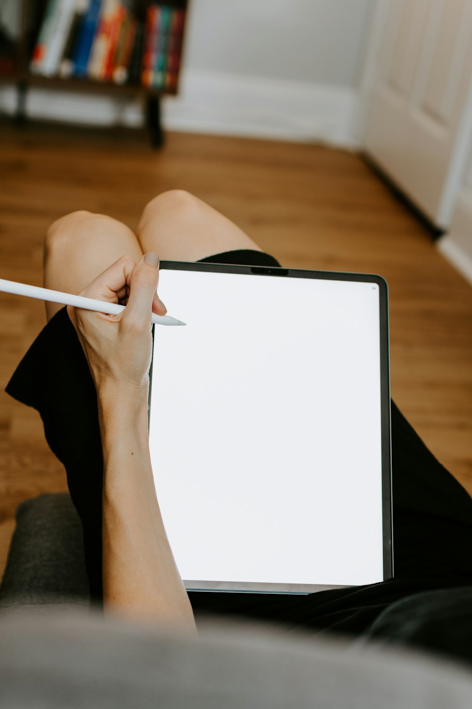 Une personne utilise un stylet sur une tablette numérique posée sur ses genoux.